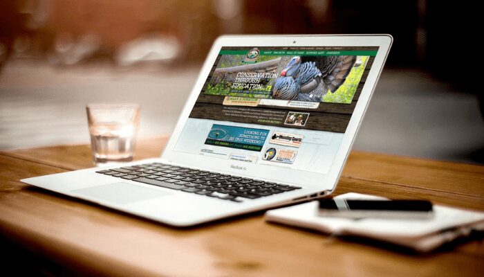 The images shows a latop on a office desk. A website is being designed on the laptop